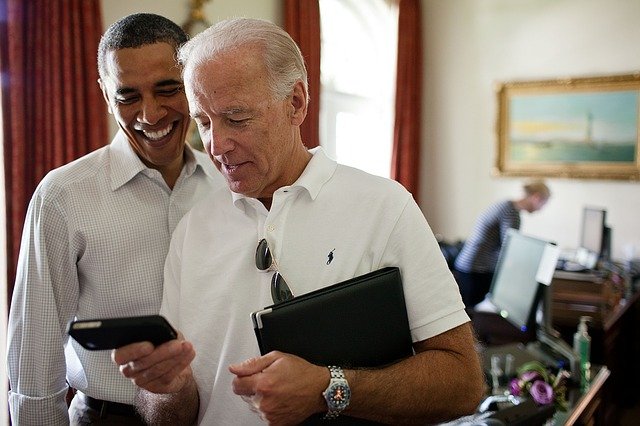 Barack Obama und Joe Biden schauen auf ein Smartphone
