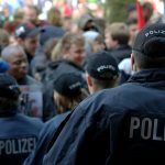 1300 Polizist*innen in Hamburg haben einen Nebenjob Polizisten von hinten im Einsatz bei einer Demonstration.