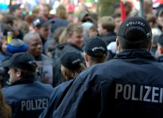 1300 Polizist*innen in Hamburg haben einen Nebenjob Polizisten von hinten im Einsatz bei einer Demonstration.