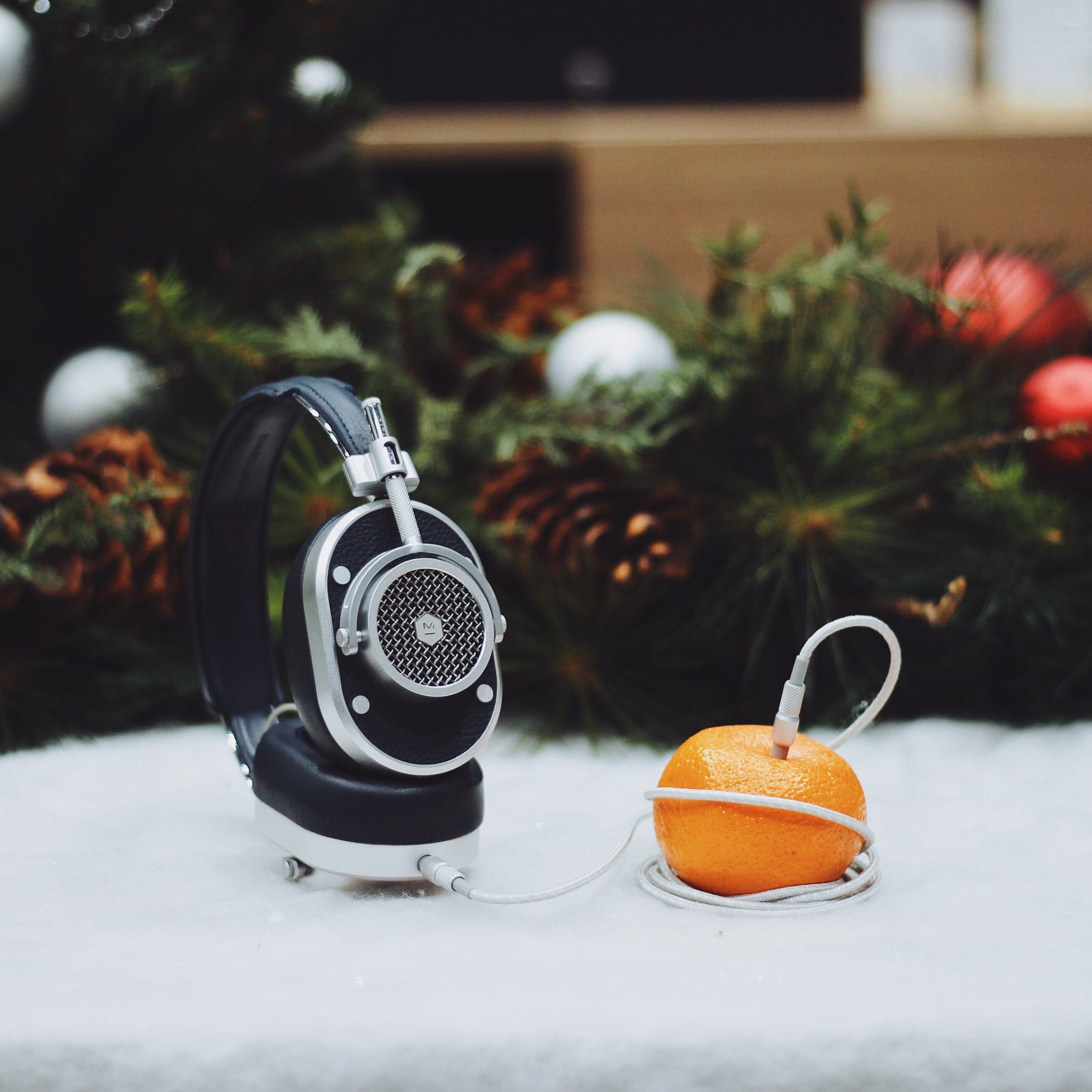 Ein Kopfhörer steckt in einer Orange und steht symbolisch für Weihnachtslieder