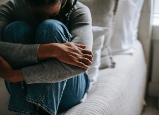 PCO-Syndrom: Gestörte Hormone, unerfüllter Kinderwunsch Frau sitzt auf Bett. Arme um Körper geschlungen