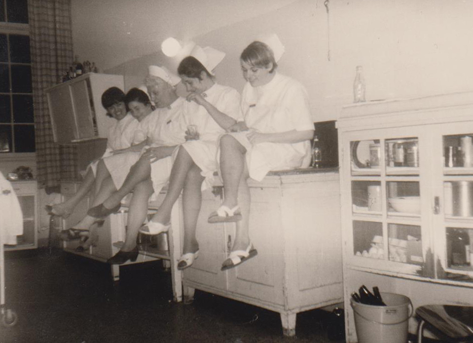 Hebammen und Schülerinnen sitzen auf einem Schrank in einem Kreißsaal in der Frauenklinik FInkenau im Jahr 1968/69.