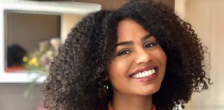 Afrohaare: Zwischen Pflege und Empowerment Afrohaare Portraitfoto von Abina Ntim. Sie trägt ihre gelockten, schulterlangen Afohaare offen und lächelt.