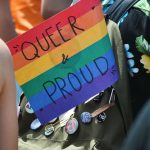 Kostenlose Ferienangebote für queere Jugendliche Regenbogenflagge, auf der Queer & Proud steht in einem Rucksack.