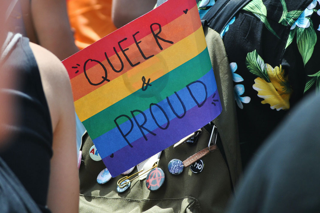 Regenbogenflagge, auf der Queer & Proud steht in einem Rucksack.