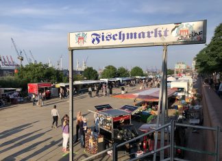 Schoko Jonny, Jessy und Herr Peters: Drei Fischmarkt-Originale feiern Wiedereröffnung Eingang zum Fischmarkt Hamburg an einem sonnigen Tag.