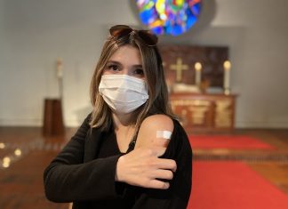 Links impfen, rechts beten Eine Frau zeigt ihren Arm mit einem Pflaster, das sie nach der Impfung bekommen hat.