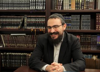 „Wo es Coca-Cola gibt, da gibt es auch Chabad“ Rabbiner Arye Merkhasin vom Chabad Hamburg sitzt vor einer Wand aus Büchern.