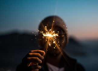 Silvester in Hamburg: Wie dürfen wir feiern? Ein Mann mit Mütze hält eine Wunderkerze ins Bild. Außer der Wunderkerze ist alles verschwommen.