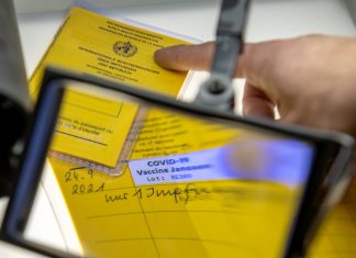 Gefälschte Impfpässe: Hamburger Polizei gründet Sonderkommission Abbildung einer aufgeschlagenen Impfpassfälschung und einer Lupe. Foto: Stefan Puchner/dpa.