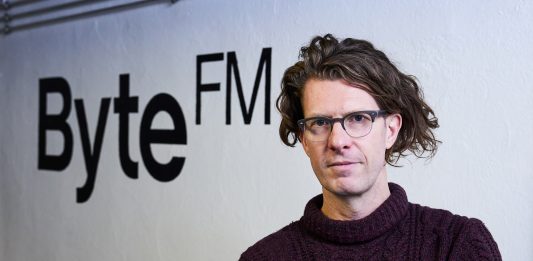 “Es braucht in Zukunft nicht mehr 100 Sender, die alle gleich klingen” Ruben Jonas Schnell vor dem ByteFM-Logo.