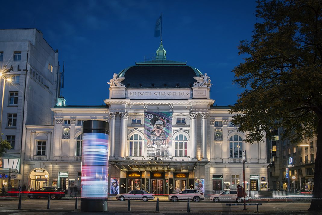 Außenansicht des Deutschen Schauspielhauses bei Nacht. Im Vordergrund ist eine Litfasssäule beleuchtet.