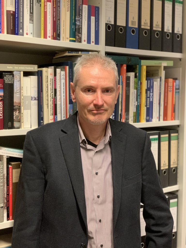 Der Historiker Christoph Strupp steht vor einer Bücherwand in seinem Büro. 