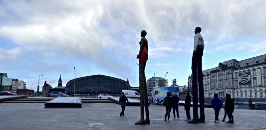 Menschen versammeln sich unter den großen Figuren auf dem Arno-Schmidt-Platz beim Hambuger Hauptbahnhof