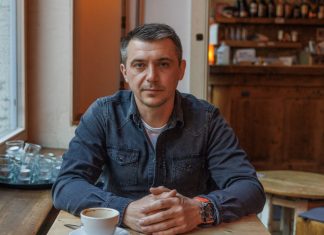 “Deutsch zu lernen hat jetzt Priorität” Ilya trägt ein blaues Hemd und guckt ernst in die Kamera