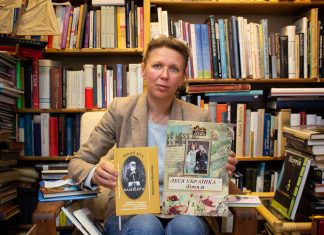 “Eigentlich sind wir ein deutsch-ukrainisches Kulturzentrum geworden” Buchhändlerin Natalia Banakh sitzt auf einem Stuhl und zeigt ukrainische Bücher