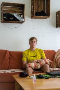 Tennis player Yehor Opanasenko sits on a sofa in his apartment, a pillow in his lap.
