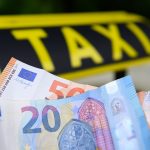 Höhere Preise für Taxifahrten in Hamburg Taxifahren in Hamburg wird teurer. Geldscheine vor einem Taxi-Schild.