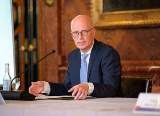 Haushaltsplan 2023/2024: So steht es um Hamburgs Finanzen Hamburgs Erster Bürgemeister Peter Tschentscher sitzt am Tisch und spricht ein ein Mikro.