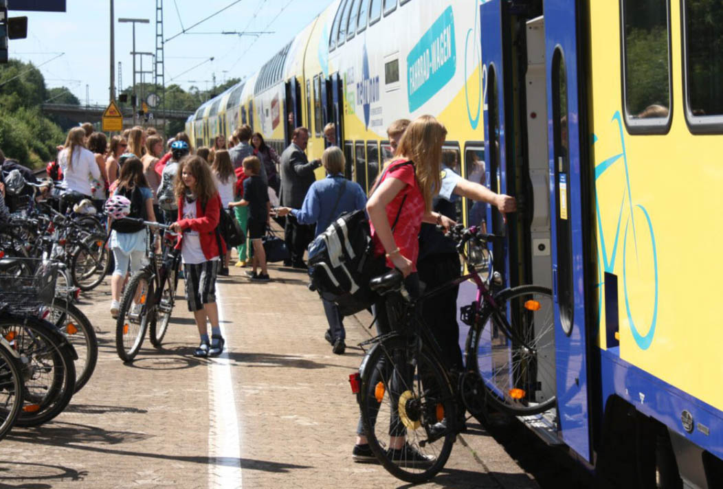 Fahrräder im Metronom. Menschen stehen am Bahnsteig mit ihren Fahrrädern und möchten in den Metronom einsteigen.