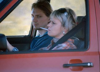 Ukraine im Film Ukrainischer Film My Thoughts Are Silent. Man sieht einen jungen Mann und eine Frau mit Zigarette im Mund in einem roten Auto sitzen.