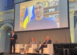 Wladimir Klitschko: “Sicherheit ist zerbrechlich” Pakt Hamburg Kiew ist das Diskussionsthema. Im Börsensaal der Handelskammer Hamburg. Wladimir Klitschko ist live auf einer großen Leinwand zugeschaltet. Auf der Bühne sitzen Peter Tschentscher, Tatjana Kiel und Malte Heyne.