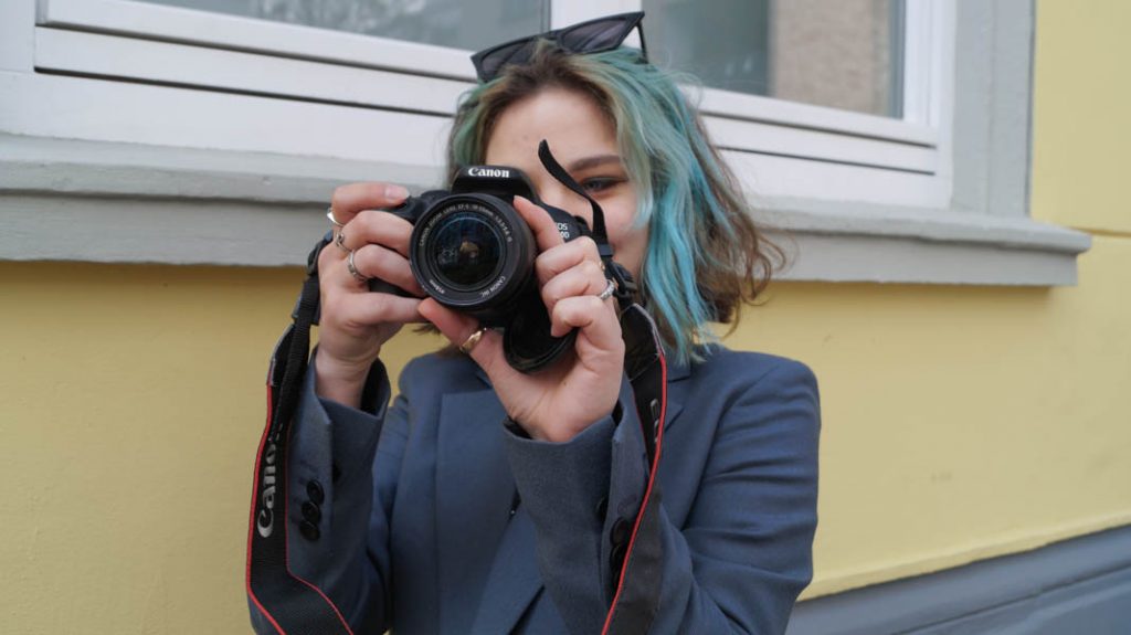 Ukrainische Journalistin hält sich ihre Kamera vor das Gesicht.