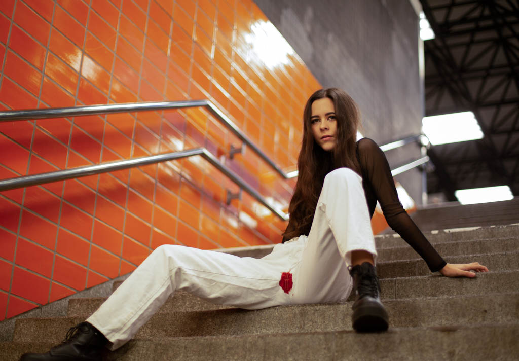 Tabu Periode: Frau mit blutiger Hose sitzt auf einer Treppe.
