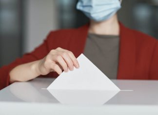 Your Choice an der HAW: Warum du zu den Hochschulwahlen gehen solltest Hochschulwahlen HAW. Frau wirft Umschlag in Wahlurne.