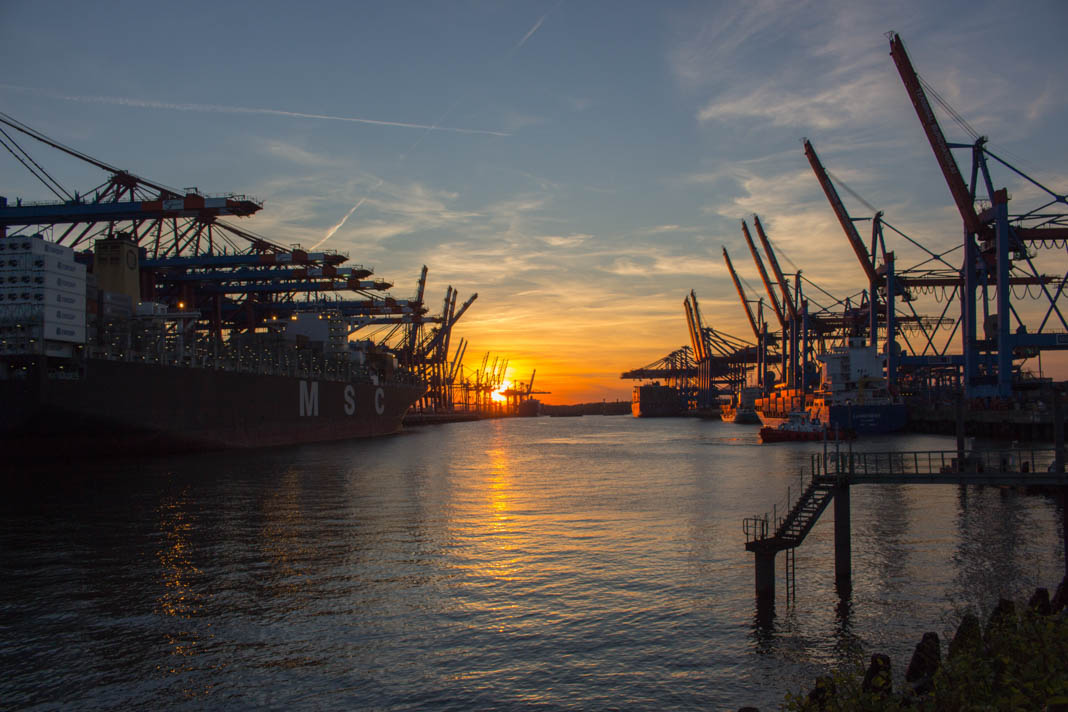 Der Hamburger Hafen bei Sonnenuntergang. Links und rechts sieht man die Kräne.
