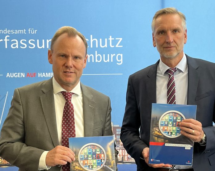Andy Grote und Torsten Voß vor einer Pressewand. Sie präsentieren den Verfassungsschutzbericht 2021.