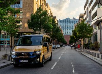 Sammeltaxis fahren ab 2023 in mehr Stadtteilen Ein goldenes Moia Sammeltaxi auf einer Straße in Hamburg. Im Hintergrund sieht man die Elbphilharmononie. Foto: Moia
