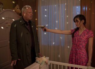 Diese fünf feministischen Filme müsst ihr sehen Auf dem Bild sieht man eine Frau und einen Mann in einem Kinderzimmer sich gegenüber stehen. Die Frau trägt eni tief ausgeschnittenes, rosa Kleid und zielt mit eine Pistole auf den Mann, der eine dunkle Jacke trägt