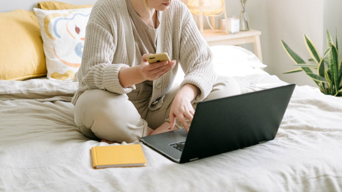 Suchtberatung jetzt auch digital: Frau sitzt auf ihrem Bett am Laptop