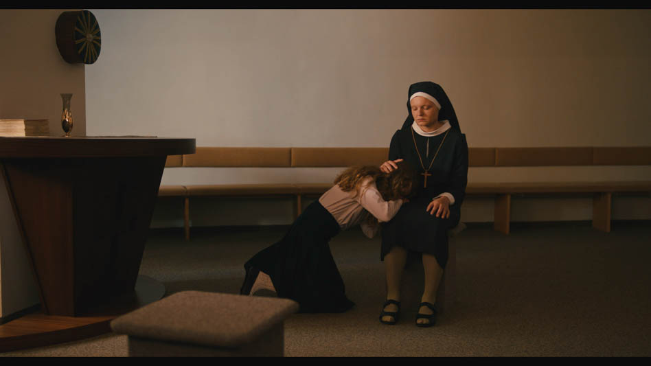 Rezension Serviam - Ich will dienen:Die Schwester sitzt in einem Raum, Martha legt ihren Kopf in ihren Schoß