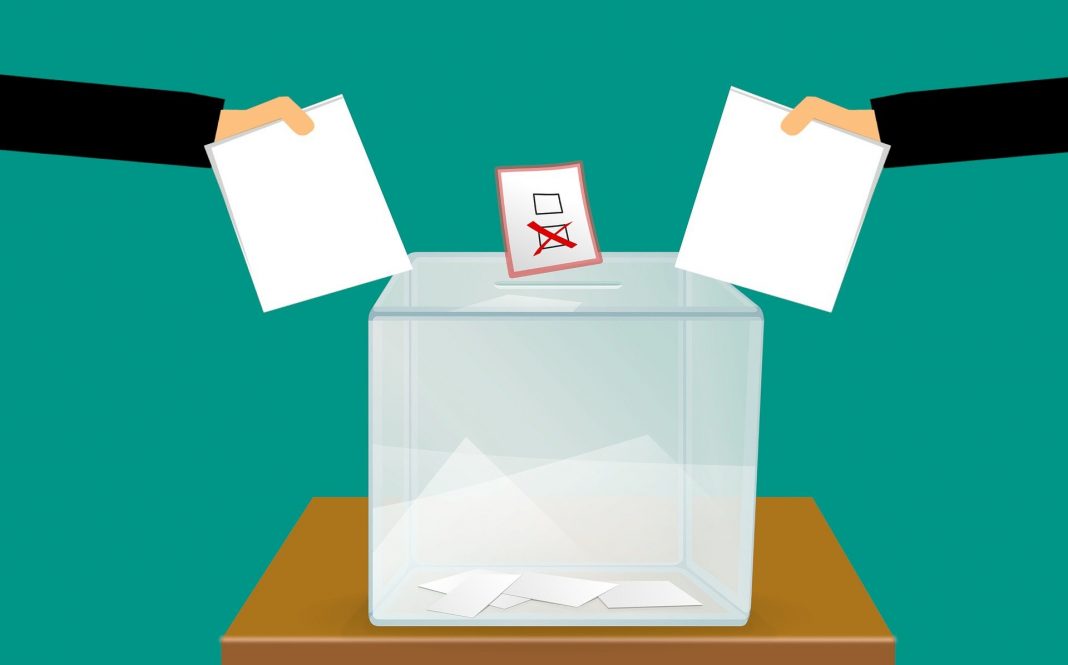 StuPa HAW: In der Mitte steht eine Wahlurne. Rechts und links sind Hände mit Wahlzetteln zu sehen.
