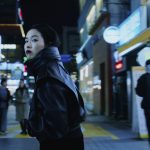 „Ohne Rückkehr“: Pokerface auf Identitätssuche Ohne Rückkehr: Protagonistin Freddie dreht sich in beleuchteter Einkaufsstraße um und trägt eine schwarze Lederjacke