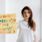 Internationaler Tag gegen Gewalt an Frauen Eine Frau, die gegen Gewalt an Frauen protestiert. Sie hält ein Schild mit der Schrift "Womens Rights are Human Rights" hoch.
