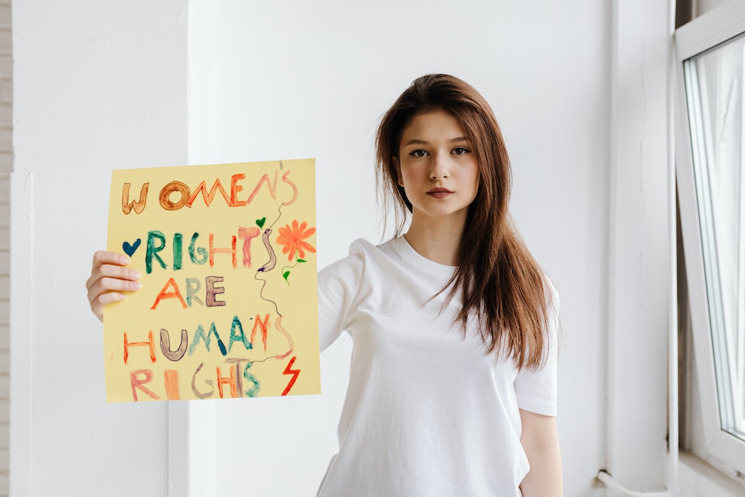 Eine Frau, die gegen Gewalt an Frauen protestiert. Sie hält ein Schild mit der Schrift "Womens Rights are Human Rights" hoch.