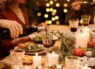Weihnachten mit der Familie – und internationalen Studenten Eine gedeckte Tafel bei gemütlichem Licht. Es wird gerade Rotwein eingeschenkt.