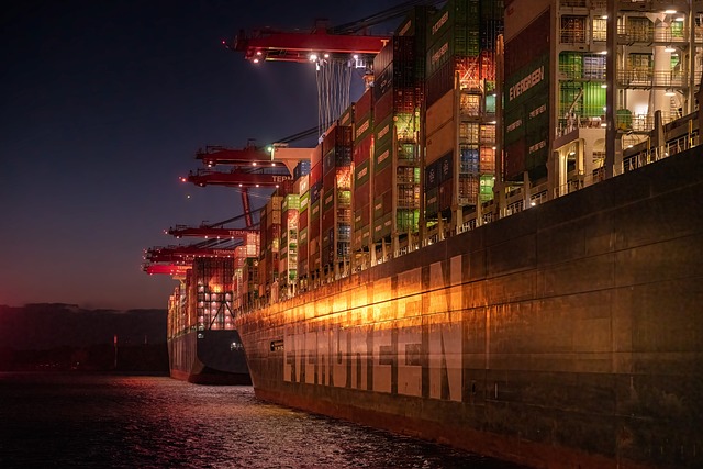 Ein Containerschiff wird angestrahlt. Es ist schon dunkel. Der Hamburger Hafen soll klimaneutral werden.
