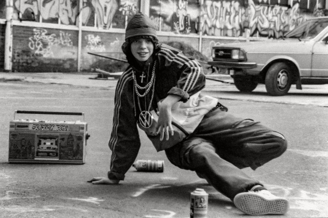 Sprüher Jace am Breakdancen vor seinem Werk und einem Ghettoblaster. Hamburgs Graffiti Geschichte. Foto: Jennifer Kauka
