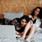 Diese alternativen Weihnachtsfilme locken selbst den Grinch hervor Zwei Frauen liegen auf dem Bett vor einem Laptop