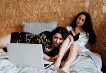 Diese alternativen Weihnachtsfilme locken selbst den Grinch hervor Zwei Frauen liegen auf dem Bett vor einem Laptop