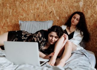 Diese alternativen Weihnachtsfilme locken selbst den Grinch hervor Zwei Frauen liegen auf dem Bett vor einem Laptop