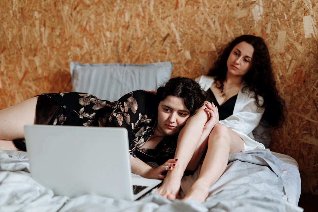 Zwei Frauen liegen auf dem Bett vor einem Laptop