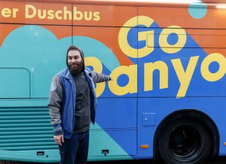 Verdienstorden für den Initiator des ersten Hamburger Duschbusses Verdienstorden für Dominik Bloh: Der GoBanyo Projektinitiator, zeigt auf das Logo des Duschbusses. Foto: Markus Scholz/ dpa