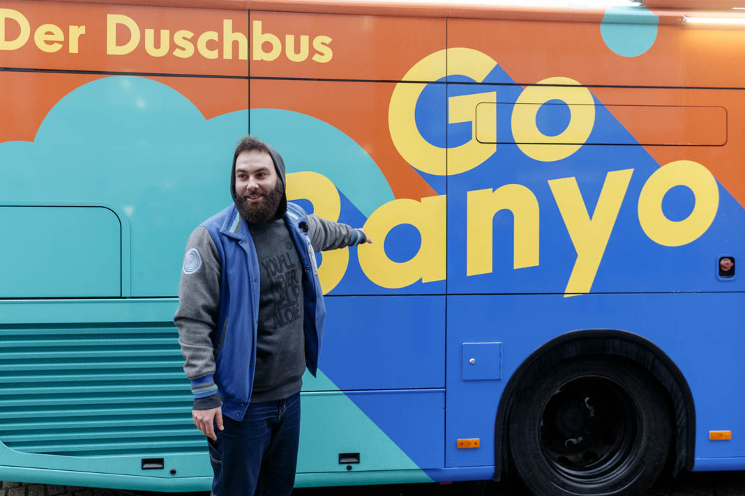 Verdienstorden für Dominik Bloh: Der GoBanyo Projektinitiator, zeigt auf das Logo des Duschbusses. Foto: Markus Scholz/ dpa