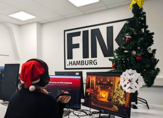 Unsere liebsten Weihnachtssongs Weihnachtssongs : Lieblinge der FINK-Redaktion. Redakteurin Sarah Böse sitzt am Computer mit Kopfhörern an, im Hintergrund ein Weihnachtsbaum und das FINK.HAMBURG Logo auf einer Wand.