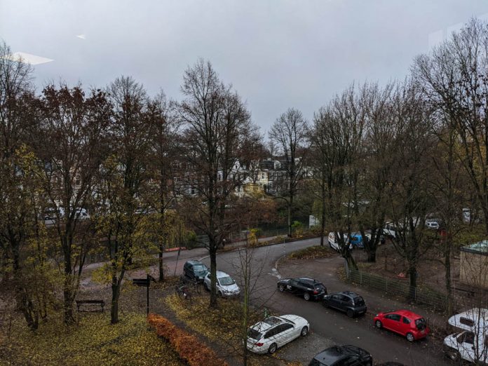 Grauer Himmel, karge Bäume entlang eines Kanals in Hamburg, parkende Autos an einer kleinen Straße.
